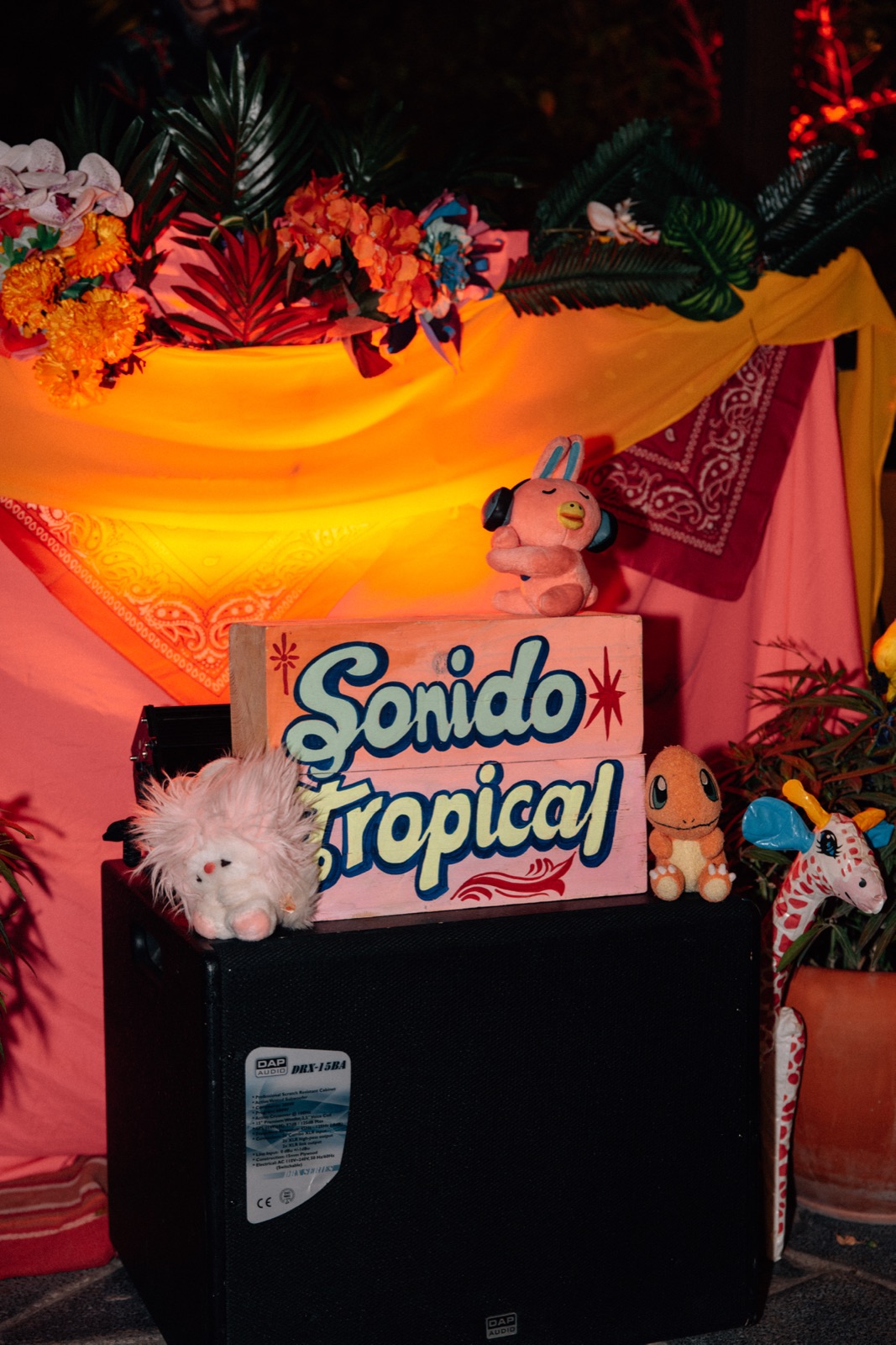 A decorated stall with a Sonido Tropical sign, flowers and bright fabric.
