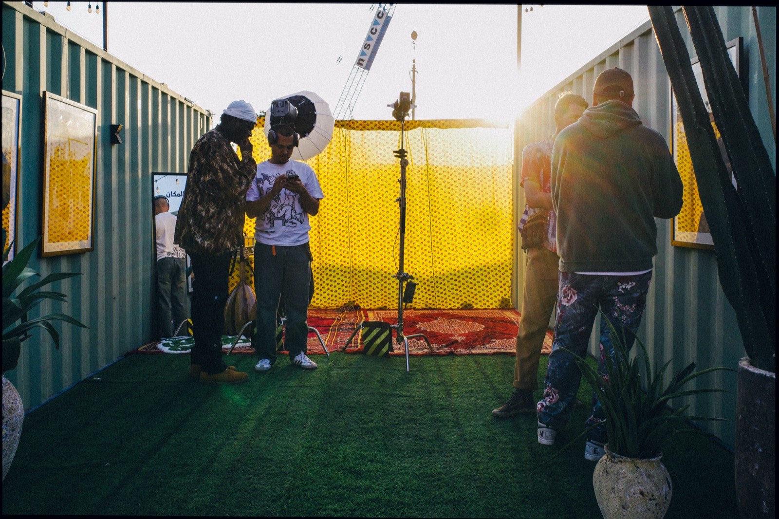 People gathered between shipping containers in the late afternoon sun.