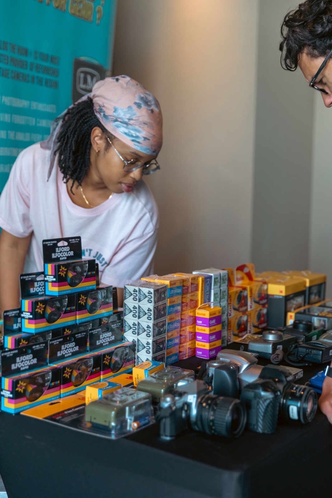 A person arranging boxes of camera film and cameras on a stall.