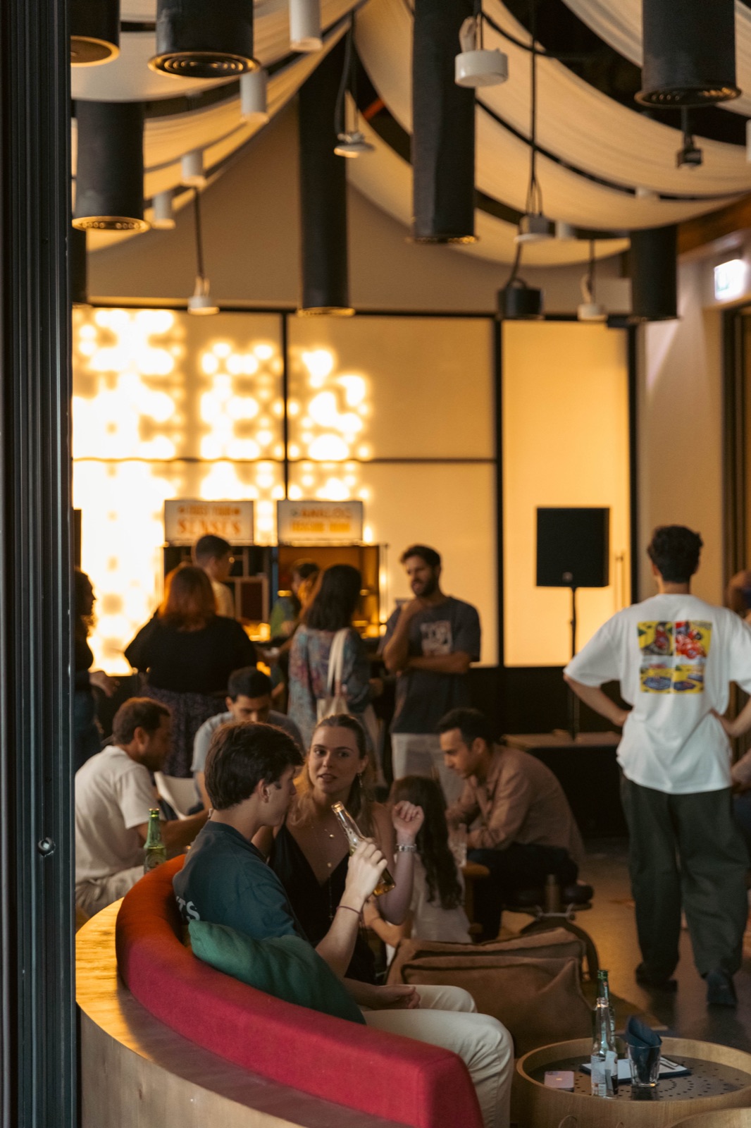 A seated crowd listening in a room with a wall of lights.