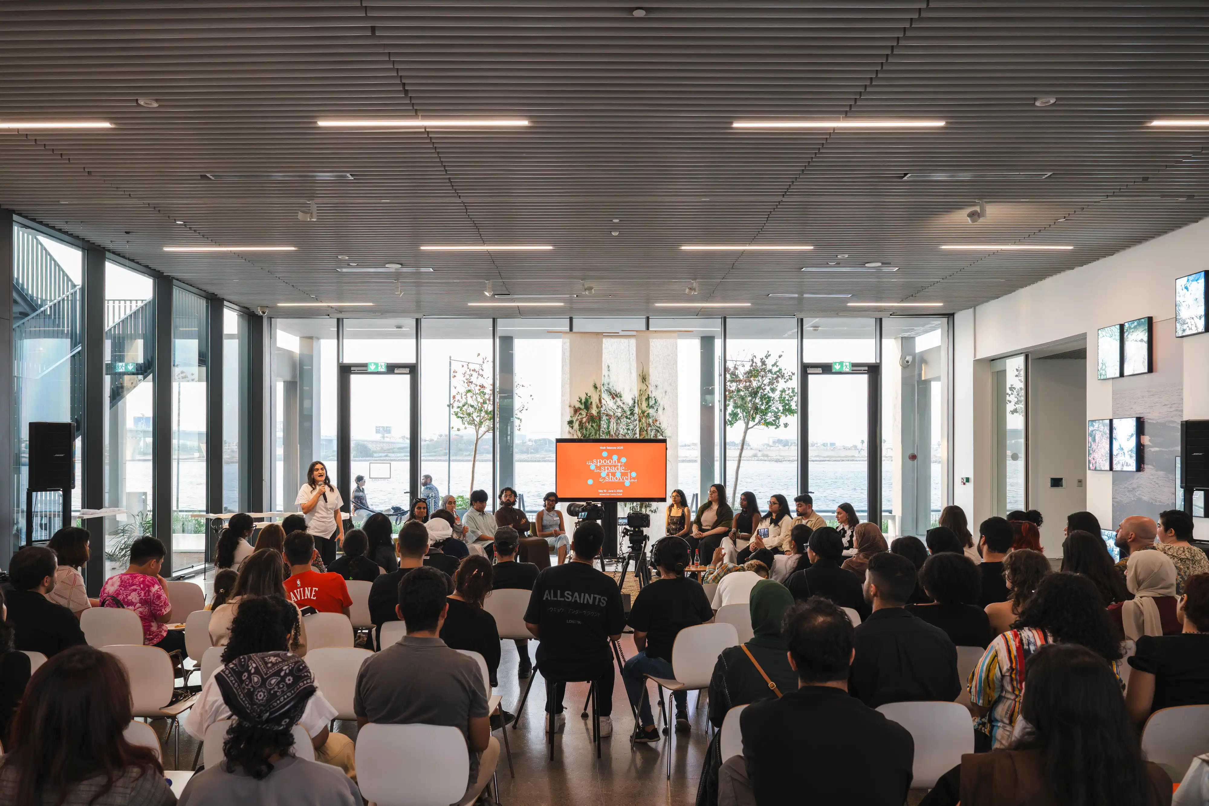 A panel discussion taking place in front of a seated crowd within the Jameel Arts Centre.