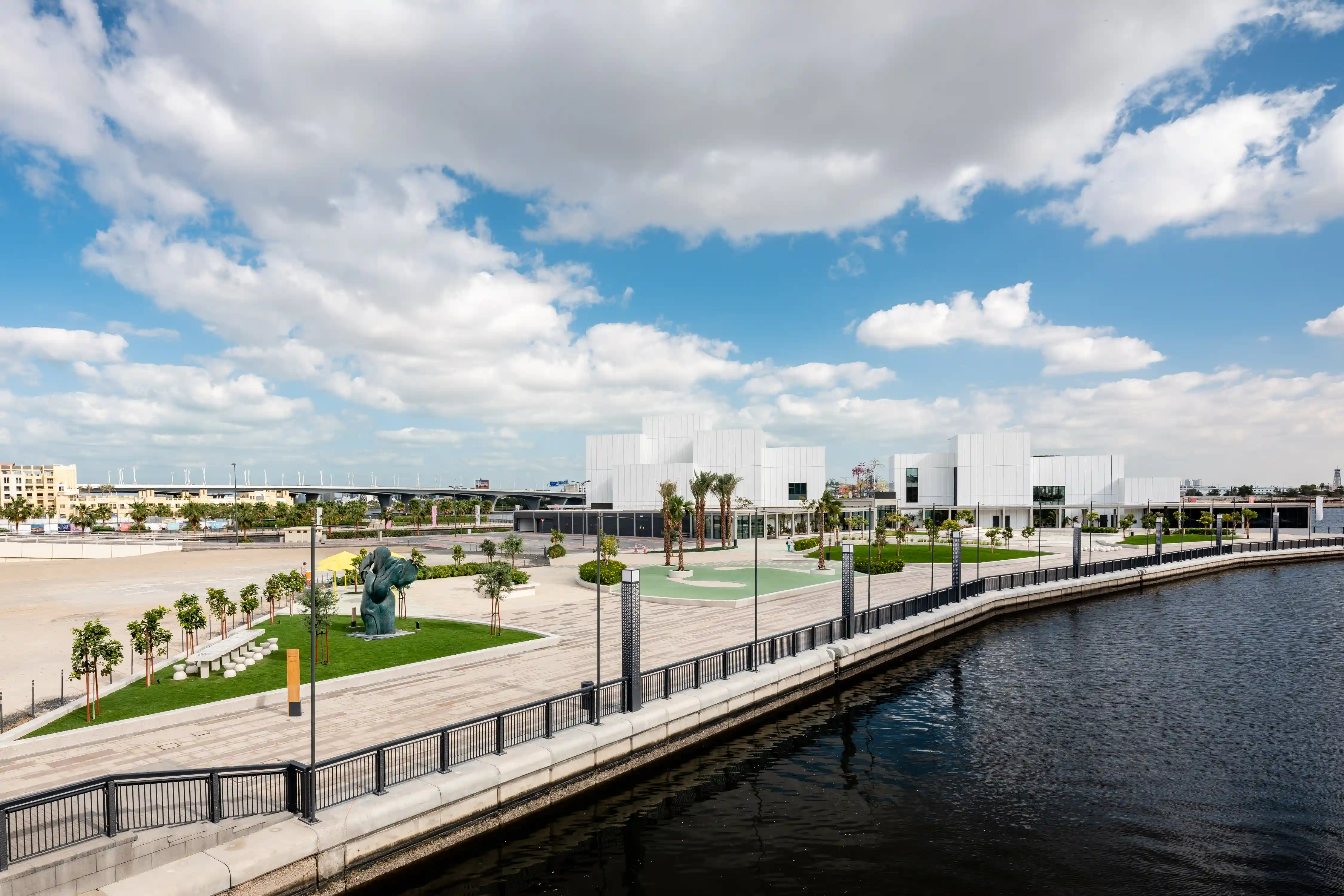 Scenic view of the Jaddaf Waterfront Sculpture Park in front of Jameel Arts Centre, accompanied by the creek on the side.